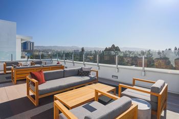 a roof top patio with couches and tables overlooking a city
